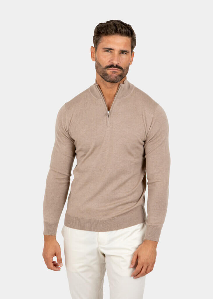 Model wearing a sand Merino wool quarter zip sweater, front view.
